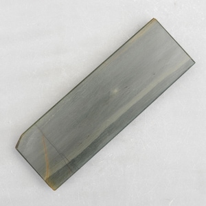 Può includere: Una pietra per affilare rettangolare grigia con una superficie leggermente ruvida.