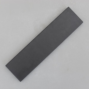 May include: A long, rectangular object in dark grey with a matte finish. The item has a slightly textured surface and is angled diagonally. It is set against a light grey background.