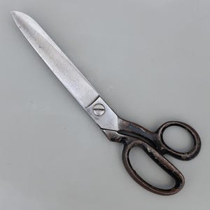 May include: Vintage metal scissors with a pointed blade and dark brown handles. The silver blades are joined by a screw. The handles feature two finger holes. The scissors are approximately 25 cm long.