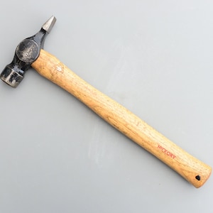 May include: A black and silver hammer with a wooden hickory handle. The hammer has a claw on the back and the handle is marked "Hickory".