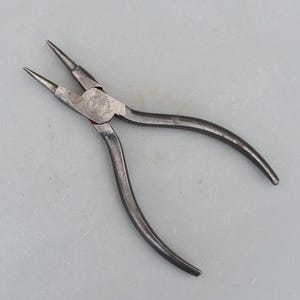 Peut inclure: Une paire de pinces argentées avec des pointes pointues. Les pinces sont conçues pour la fabrication de bijoux ou d'autres tâches délicates.