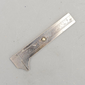 以下が含まれることがあります： エッチングされたマーキングが付いた、ヴィンテージのシルバーメタル深度ゲージ。ゲージには0〜80の測定値を持つスライドスケールと、小さな丸いリベットが付いています。このツールは深さを測定するように設計されています。