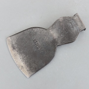 May include: A vintage, weathered metal axe head with the word "HAWKEYE" stamped on the surface. The axe head has a curved shape and a sharpened blade, showing signs of wear and use. The metal has a dark, aged appearance.