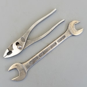 Może przedstawiać: Dwa zabytkowe narzędzia metalowe: szczypce nastawne i klucz. Klucz jest oznaczony napisem "SHEFFIELD GORDON TOOLS ENGLAND". Oba narzędzia są srebrne i wyglądają na używane, co sugeruje, że są starsze.