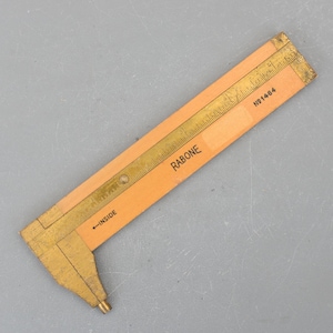 May include: A wooden ruler with a brass measuring scale and a sliding caliper. The ruler is labeled "RABONE" and "No. 1484". The caliper has a label that says "INSIDE".