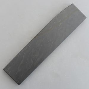 Könnte beinhalten: Ein langer, rechteckiger schwarzer Schleifstahl mit leicht abgerundeter Kante.