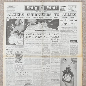 May include: A vintage newspaper page from the Daily Mail, dated November 9, 1942, with headlines about the surrender of Algiers to the Allies. The page features articles, maps, and advertisements, including one for Marmite.