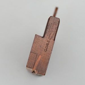 May include: A vintage wooden tool with a rectangular body and a protruding handle. The tool is made of a reddish-brown wood and features the text "C. DALE" and "TRADE MARK WARRANTED EHAM ENG".