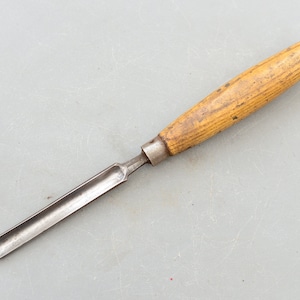 May include: A wooden handled chisel with a metal blade. The chisel is a woodworking tool used for carving and shaping wood.