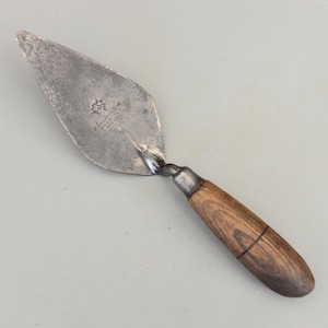 May include: A white ceramic mug with a black handle and the text "But First, Coffee" in a bold, black font. The mug is set against a blurred background, suggesting a cozy setting.