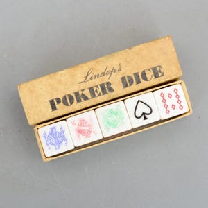 May include: A vintage set of poker dice in a cardboard box. The box is tan with the words "Lindop's POKER DICE" printed in black. The dice are white with various suit symbols and designs in red, green, blue, and black.