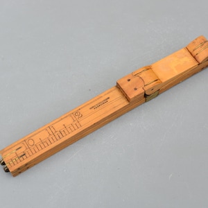 May include: A vintage wooden folding ruler, light brown with black markings and brass hinges. The ruler has inch measurements up to 12 inches (approx. 30 cm). The text "Stanley" is visible on the ruler.