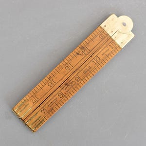 May include: A vintage wooden folding ruler with brass hinges and markings. The ruler is light brown with black numerals and measurement lines. The text "Made in England" is visible. The ruler measures up to 43 cm.