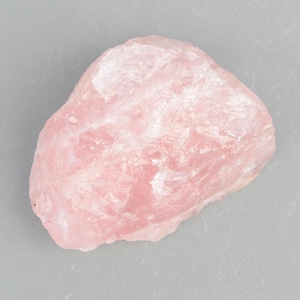 May include: A large, rough, pink rose quartz crystal. The crystal has a natural, unpolished surface.