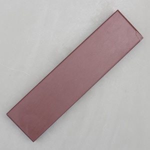 May include: A rectangular, maroon-colored sharpening stone. The stone is a solid color and has a slightly rough texture. The stone is approximately 8 inches long and 1.5 inches wide.