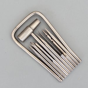 May include: A silver multi-tool set with various attachments, including a T-handle, drill bits, and files. The tools are arranged within a rectangular frame, all made of a shiny, metallic material. The set is designed for precision work and repairs.