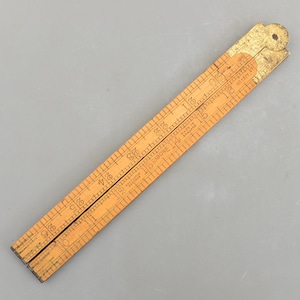 May include: A vintage wooden folding ruler, with etched measurements in inches. The ruler is light brown with dark markings and metal accents. The text "RABONE" and "ENGLAND" are visible. The ruler is approximately 66 cm long when fully extended.