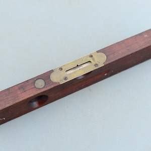 Può includere: Un livello in legno con un indicatore di livello in ottone. Il livello è contrassegnato dal numero "751".