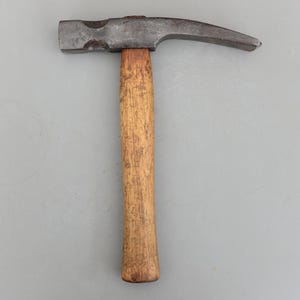 May include: A claw hammer with a wooden handle and a steel head. The hammer head has a flat striking face and a curved claw for removing nails. The wooden handle is a light brown color.
