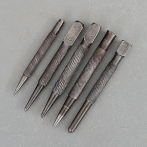 Puede incluir: Seis herramientas de punzonado de metal de diferentes tamaños y marcas. Las herramientas tienen una superficie texturizada y se utilizan para hacer agujeros en los materiales.