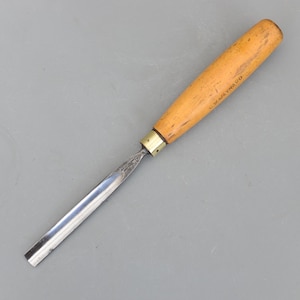 May include: A wood carving chisel with a light brown wooden handle and a silver blade. The handle has the text "C.W. MAYNARD" printed on it. The chisel is designed for detailed woodworking and carving projects.