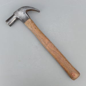 May include: A claw hammer with a wooden handle and a steel head. The hammer's head is silver and has a curved claw for removing nails. The handle is made of light brown wood.
