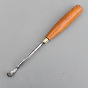 Op de afbeelding: Een houtsnijbeitel met een gebogen lemmet. De handgreep is gemaakt van gepolijst hout en het lemmet van metaal. De guts is ontworpen voor gedetailleerde houtbewerking en snijprojecten.