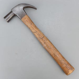 May include: A claw hammer with a wooden handle and a steel head. The hammer head is marked with the brand name "STANLEY". The claw hammer is a hand tool used for driving nails into wood and other materials.