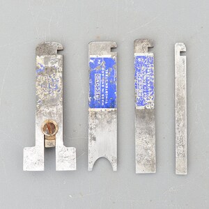 Op de afbeelding: Vier zilveren metalen gereedschappen met blauwe labels met de tekst "Record Made in England Tungsten Steel".