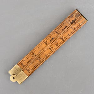 May include: A vintage wooden folding ruler with brass end pieces. The ruler is marked with inch measurements from 13 to 18. The wood has a warm, natural tone, and the brass has a slight patina. The ruler is a classic tool.