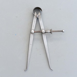 Könnte beinhalten: Eine silberfarbene Metall-Messschraube mit einem Schraubverstellknopf. Die Messschraube wird verwendet, um den Innendurchmesser von Objekten zu messen.