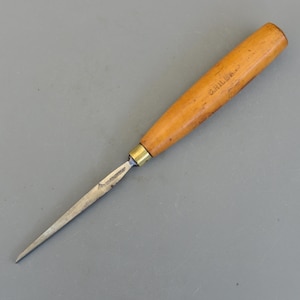 May include: A woodworking tool with a wooden handle and a metal blade. The handle is light brown with visible grain and the blade is silver. The tool appears to be a chisel or a similar instrument used for carving or shaping wood.