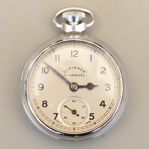 May include: A silver pocket watch with a cream-coloured face. The watch features black numerals and hands, and a small seconds dial. The face reads "DEFIANCE H SAMUEL".