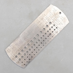 Puede incluir: Una tabla de calibre de taladro y alambre de metal vintage de The L.S. Starrett Co. de Athol, Massachusetts. La herramienta de color plateado presenta numerosos orificios perforados de varios tamaños, junto con texto impreso que indica tamaños de rosca, tamaños de broca y equivalentes decimales.