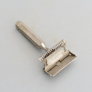 Może przedstawiać: Srebrna maszynka do golenia z grzebieniem i wygrawerowanymi napisami "Ever-Ready" i "Zapatentowany w listopadzie 1909".