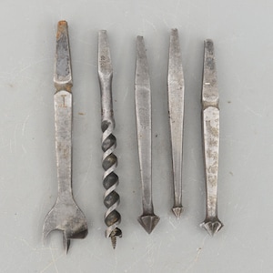 Puede incluir: Conjunto de seis brocas de metal vintage, que incluyen una broca de espiral, una broca de punta de brad y cuatro brocas de punta. Las brocas son de varios tamaños y tienen un acabado plateado.