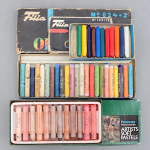 以下が含まれることがあります： ヴィンテージのアート用品の詰め合わせ。Filiaのオイルパステルがいくつか、Rowney Artists Soft Pastelsの箱が1つ含まれています。Filiaの箱は黒色でカラフルな文字が書かれており、様々なパステルカラーが入っています。Rowneyの箱は緑と白です。