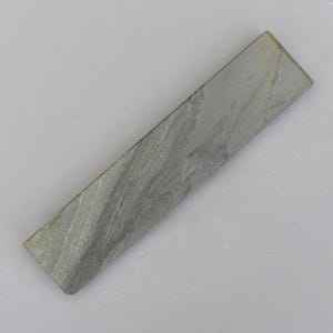 May include: A grey rectangular sharpening stone with a textured surface.