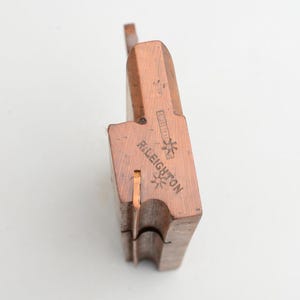 May include: A wooden hand plane with a copper finish. The plane is labelled "R. Leighton" and has a star design.