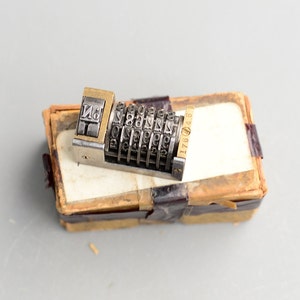 以下が含まれることがあります： 真鍮製のハンドルが付いたヴィンテージメタルナンバースタンプ。スタンプには、各ホイールに0〜9の数字が刻まれたホイールが6つあります。スタンプは、側面に17871と印刷された小さな段ボール箱に入っています。