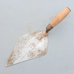 Può includere: Una cazzuola vintage color argento con manico in legno. La cazzuola è contrassegnata con "W.H.S. HUNT & SONS BRADES".