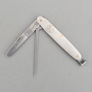 May include: A silver-toned multi-tool pipe knife featuring a folding blade, a tamper, and a pick. The blade is engraved with a pipe icon and the text "RODGERS SHEFFIELD ENGLAND". The handle displays a shield logo with the text "Rodgers".