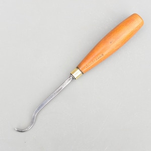 Puede incluir: Una gubia para tallar madera con una hoja curva y un mango de madera. El mango es de color marrón claro con el texto "J. H. Nystrom" impreso. La hoja es plateada y tiene forma curva.