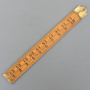 Puede incluir: Una regla plegable de madera vintage con accesorios de latón. La regla está marcada con medidas en pulgadas de 1 a 23, y el texto "Made in England" es visible. La regla mide aproximadamente 61 cm de largo cuando está completamente extendida.