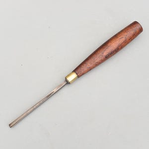 May include: A woodworking chisel with a dark brown wooden handle and a metal blade. The handle has a brass ferrule and the blade is silver. The chisel is designed for detailed woodworking tasks.