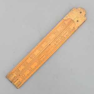 May include: A vintage wooden folding ruler, featuring etched measurements in inches. The ruler is light brown with visible wear and tear, and the numbers are clearly marked. The ruler is marked "RABONE" and "MADE IN ENGLAND".