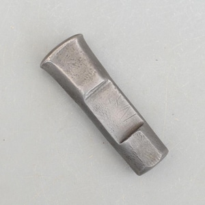 May include: A grey metal chisel with a rectangular head and a slightly tapered handle. The chisel has a small inscription on the side.