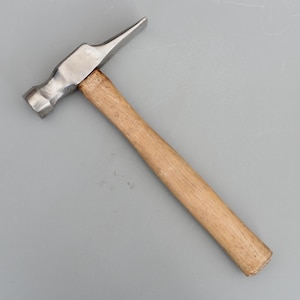 May include: A metal hammer with a wooden handle. The hammer head has a flat face and a curved claw. The handle is made of light-colored wood. The hammer is designed for construction and repair work.