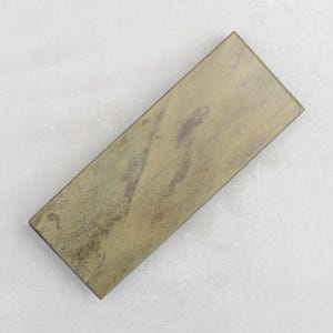 May include: A rectangular green sharpening stone with a rough, textured surface.