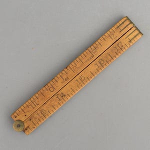 May include: A vintage folding wooden ruler with brass hinges and metal joints. The light brown wood features black printed imperial measurement markings, numbers, and the text 'MADE IN U.S.A.' and 'NO 68' clearly visible on the surface.
